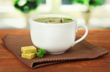 Cup of soup with bouillon cubes on wooden table