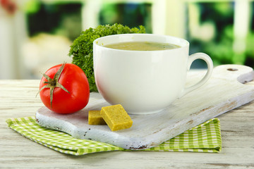 Cup of soup with bouillon cubes on wooden table