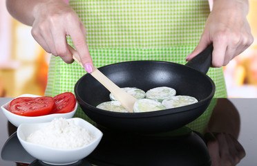 Hands cooking marrows in pan in kitchen