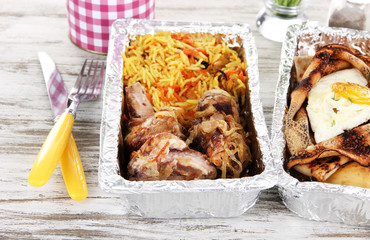 Food in boxes of foil on wooden table