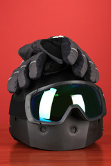 Fototapeta premium Winter sport glasses, helmet and gloves, on red background