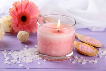 Obraz na płótnie Canvas Beautiful pink candle with flower on purple wooden background
