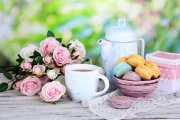 Macaroons in bowl on wooden table on natural background
