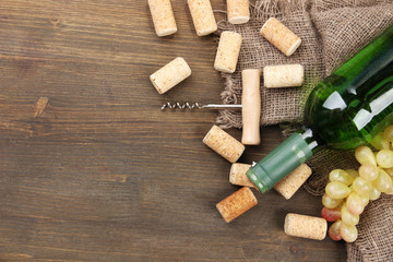 Obraz na płótnie Canvas Bottle of wine, grapes and corks on wooden background