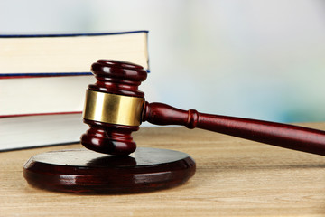 Gavel and books on table on light background