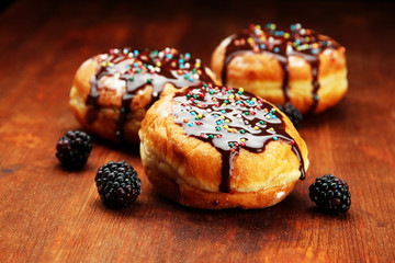 Tasty donuts with chocolate and berries on wooden table