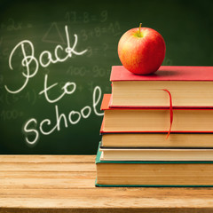 Old vintage books and apple over chaclkboard background