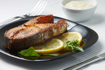 Grilled Salmon Steak with Lemon on Black Dish