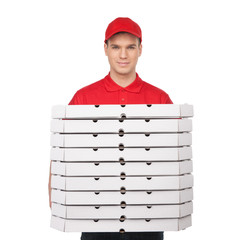 Your pizza! Young cheerful pizza man holding a stack of pizza bo