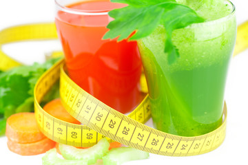 measuring tape, glass of celery juice and glass of carrot juice