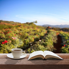 Cup of coffee and a book on a wooden table