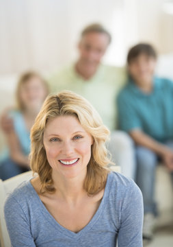 Woman Smiling With Family Sitting In Background At Home