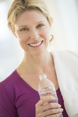 Happy Woman With Towel And Bottle Of Water In Gym