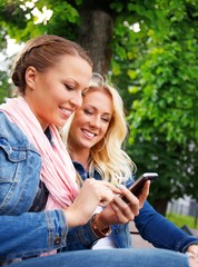 Two beautiful smiling young girl in jeans jackets 