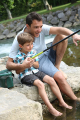 Father teaching son how to fish in river