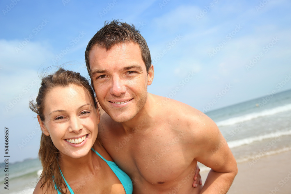 Wall mural Cheerful young couple standing on the beach