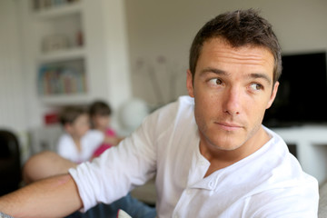 Obraz premium Portrait of man sitting in sofa, kids in background