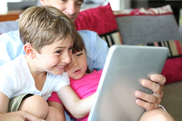 Father and children playing with tablet at home