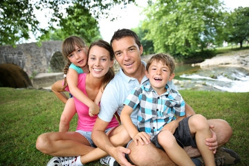 Family relaxing by river in countryside