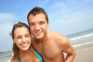 Fototapeta premium Cheerful young couple standing on the beach