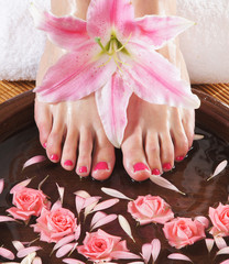 Obraz na płótnie Canvas Spa compositions of sexy female feet and plenty of petals