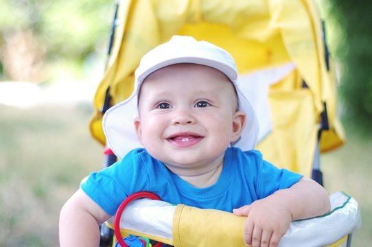 happy baby boy age of 9 months on yellow baby carriage