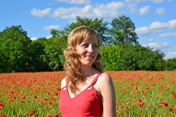 The young woman smiles in a poppy field