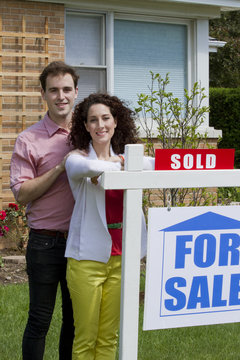 Happy couple with sold house, vertical