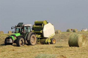 Fototapeta na wymiar Tractor collecting haystack in the field