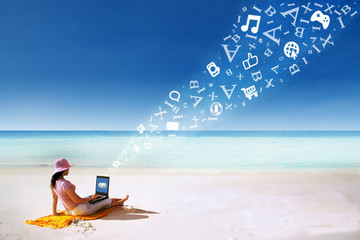 Asian woman using laptop at beach