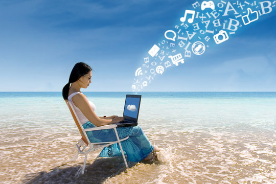 Asian female using laptop at beach