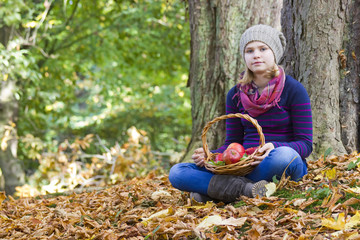 young girl with basket of apples in autumn garden