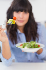 Pretty brunette showing her fork of salad to camera