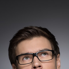 Cropped image of young men in eyeglasses looking u