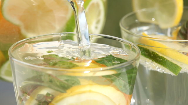 Jug with fresh lemonade pouring to glass
