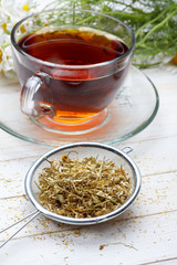 Dried chamomile and tea on wooden table