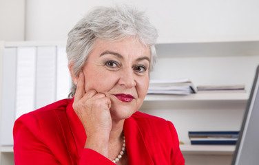 Gesicht einer grauhaarigen älteren Frau mit Falten im Büro