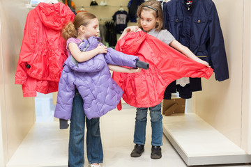 Two cute girls try on clothes in modern store