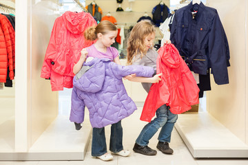 Two girls choose clothes in store childrens clothes