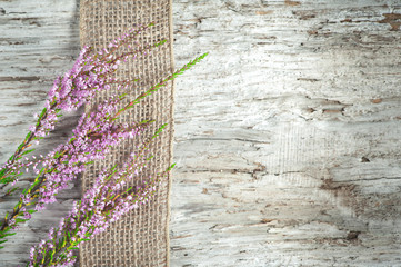 Old wooden background with heather and sacking ribbon
