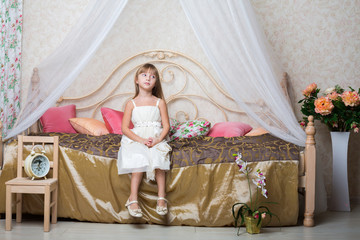 A little girl sitting on bed in bedroom decorated with flowers