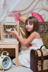 Petite fille dans la chambre jouant avec un oiseau dans une cage