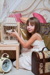 Photo sur Plexiglas Oiseaux en cages Petite fille dans la chambre jouant avec un oiseau dans une cage