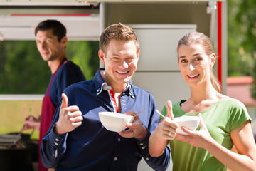Friends eating a soup on the food stall