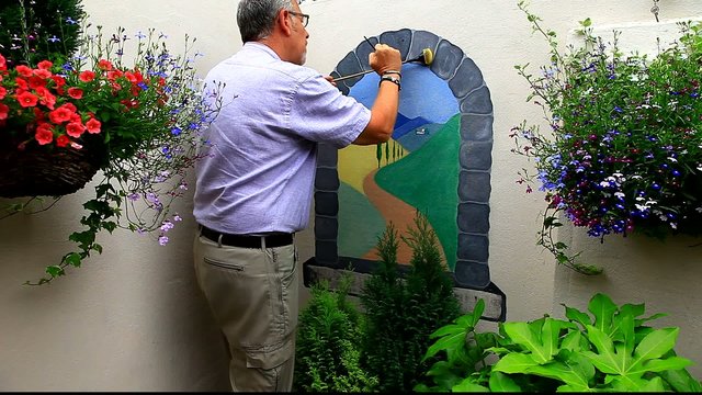 man painting mural on wall