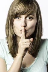 Naklejka premium Young woman holds a finger to her mouth