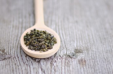 Spoon of green Tea leaves on wooden background