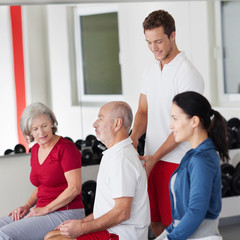 trainer berät einen älteren mann im fitnessstudio