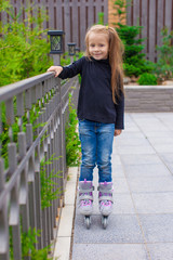 Little cute girl on roller skates in front of her home