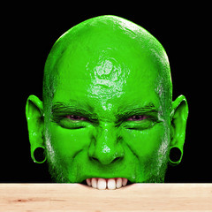Mann mit grünem Gesicht beißt in Tischkante